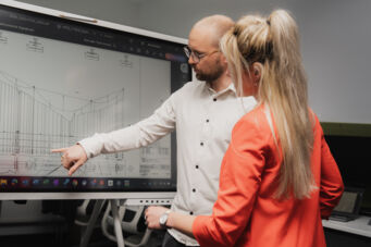 Deux collaborateurs Cteam analysent des plans techniques sur un &eacute;cran interactif.