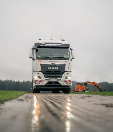 Camion blanc MAN sur un chemin boueux, avec une petite excavatrice orange en arrière-plan. Cteam : systèmes de protection des sols mobiles. Camion blanc MAN sur un chemin boueux, avec une petite excavatrice orange en arrière-plan. Cteam : systèmes de protection des sols mobiles.