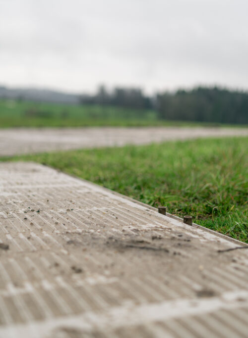 Passerelle Cteam en b&eacute;ton avec gazon et ciel couvert pour l'ext&eacute;rieur.