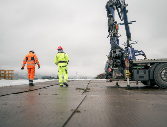 Deux travailleurs en tenue de sécurité Cteam inspectent un chantier avec grue. Deux travailleurs en tenue de sécurité Cteam inspectent un chantier avec grue.
