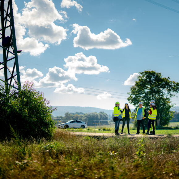 Professionnels Cteam en inspection de site &eacute;lectrique sous un ciel nuageux.